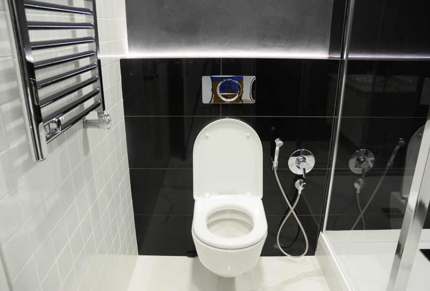 Bathroom with bidet, toilet, towel holder, and black tile wall