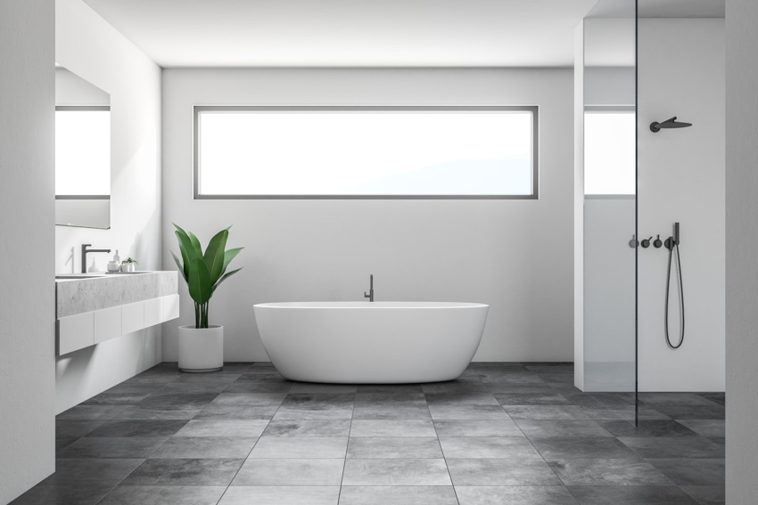 Bathroom with gray tile floor, tub, mirror, shower area, sink, and indoor plant