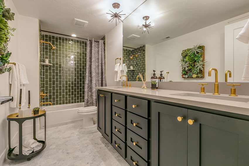 Bathroom with green cabinets shower tiles brass fixtures mirror countertop ceiling light
