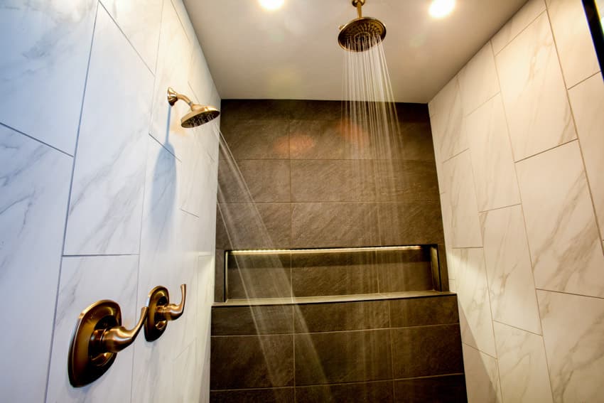 Bathroom with marble wall, brass shower heads, and ceiling light