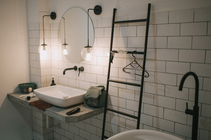 Bathroom with white tile wall, sink, mirror, and small pendant lights
