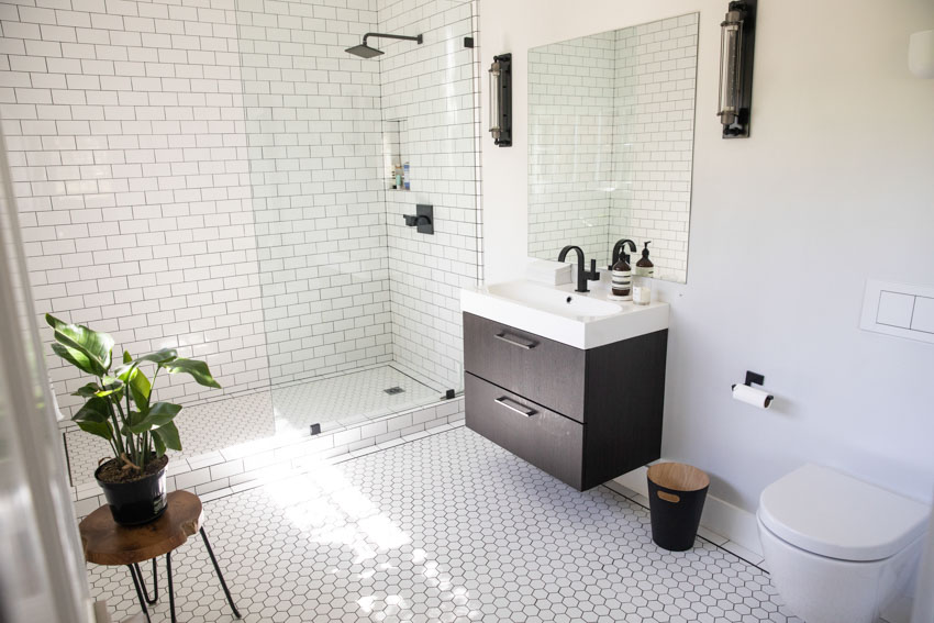 Bathroom with white tiles, mirror, toilet, and shower area