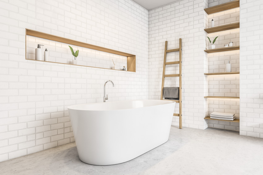 Bathroom with white tiles, recessed shelves, and tub