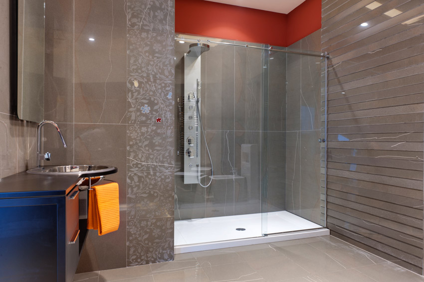 Bathroom with modern smart shower head, glass door, tile floors, mirror, and sink