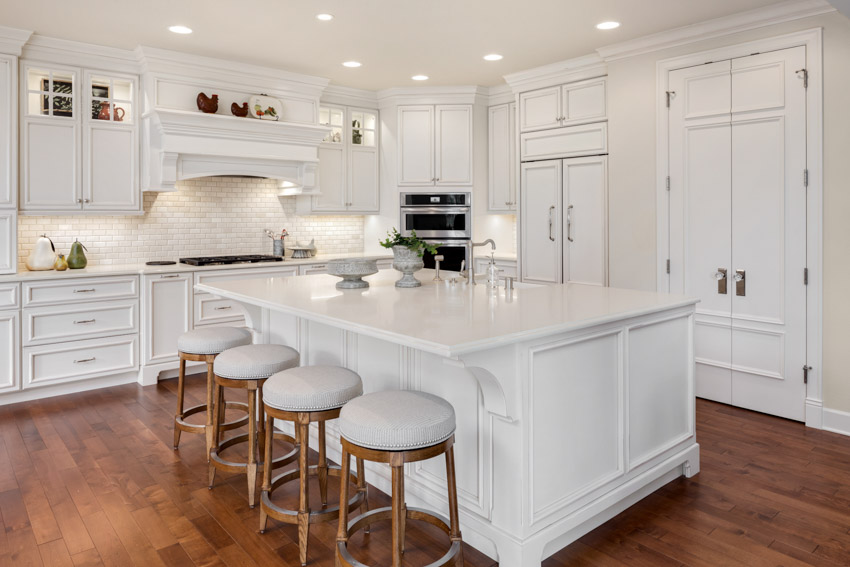 Beautiful kitchen with white cabinets, center island, wood flooring, and recessed lights