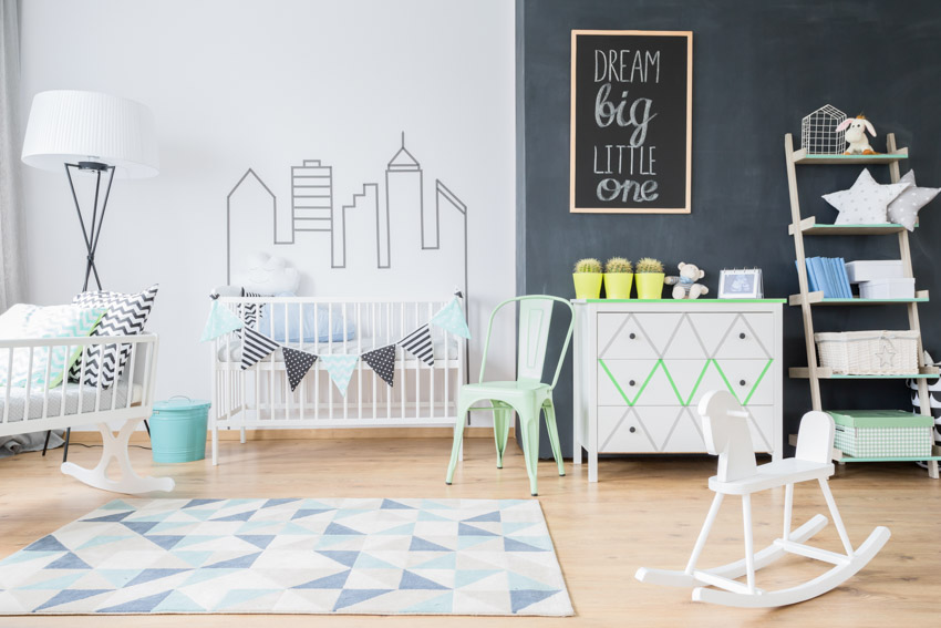 Beautiful nursery room with black and white wall, wood floor, crib, dresser, floor rug, and lamp