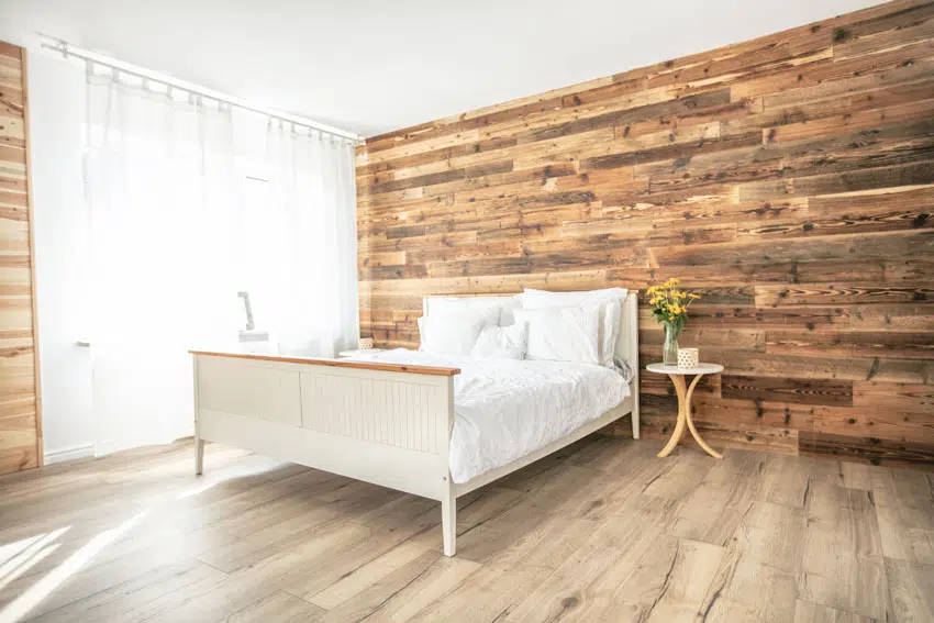 White bed with wood laminate floors and walls