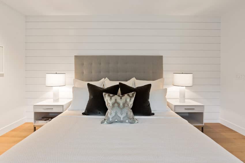 Bedroom with white accent wall, nightstands, headboard, and lamps