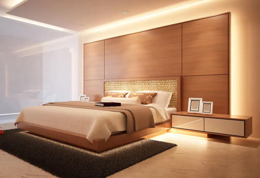 Bedroom with headboard made of wood panels with backlight, rug and side table