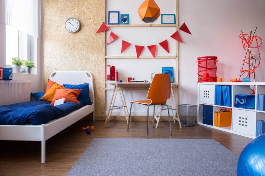 Blue and orange bedroom with study area, corkboard wall, windows, and wood floor