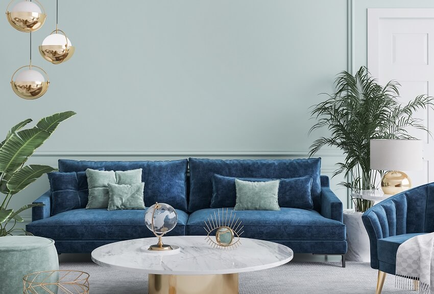 Blue sofa and armchair marble coffee table with decors on top plants stylish gold pendant and tiffany blue wall lamps in living room
