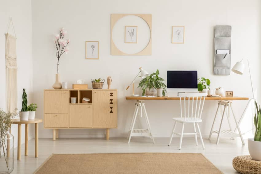 Boho inspired home office with wall decor, table, chair, rug, and indoor plants