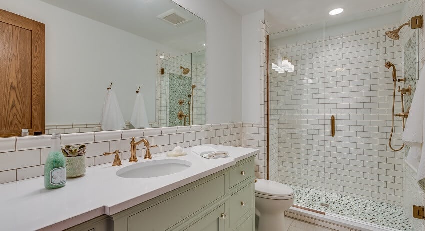 Bathroom with white subway tile wall, lighting fixtures and white countertops