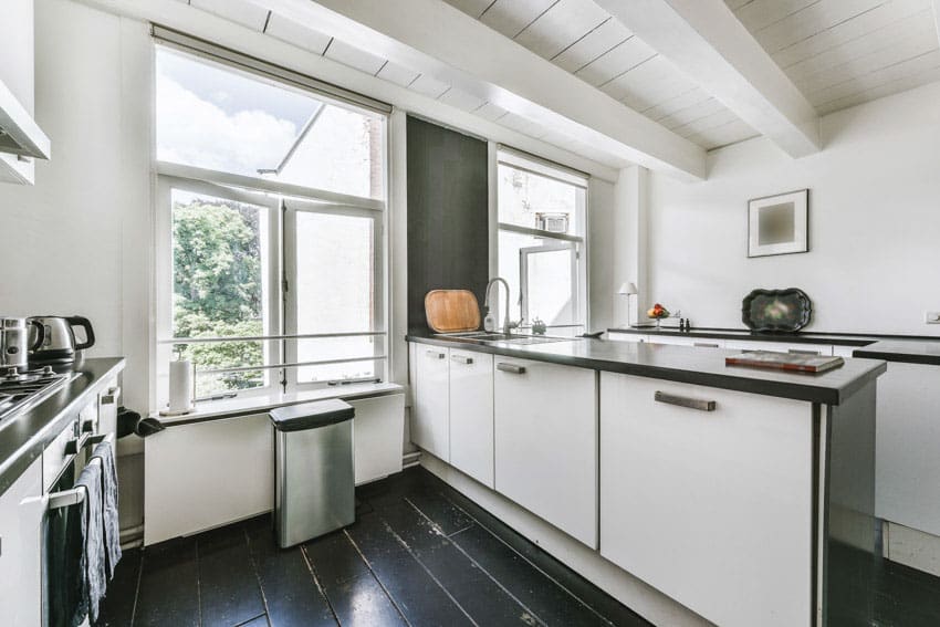 Bright kitchen space with painted ceiling beam, cabinets, center island, countertop, and windows