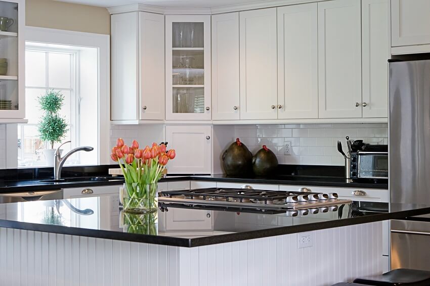 Kitchen with black granite countertops, subway tile backsplash and tulips in vase