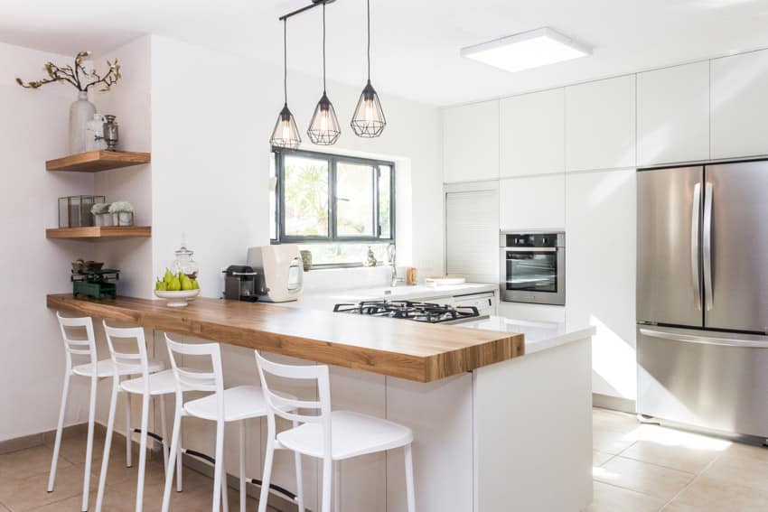 Bright prefabricated kitchen space with center island, cabinets, pendant lights, windows, and shelves