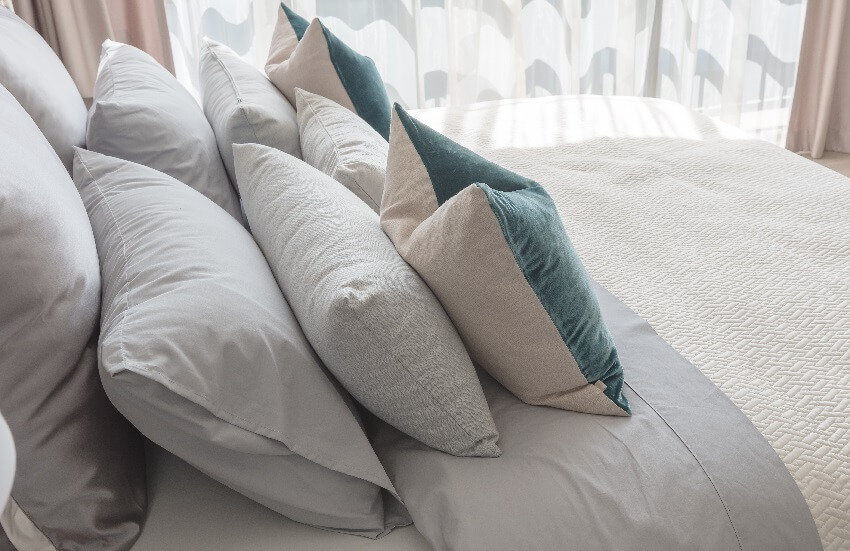 Классический стиль спальни с набором подушек в серых и синих наволочках