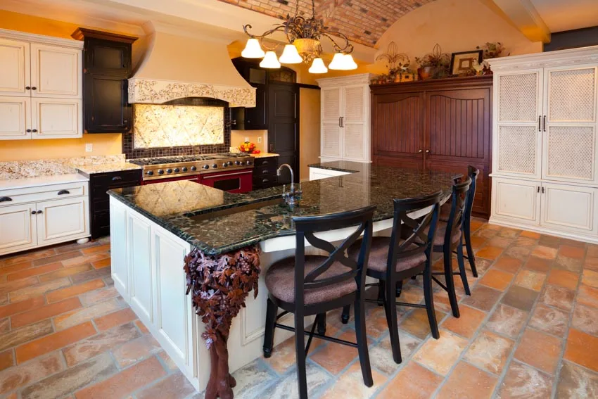 Classic kitchen with center island, gemstone countertops, chairs, pendant light, range hood, white cabinets, and stove