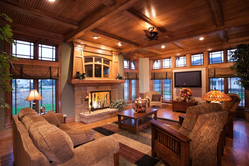 Classic living room with wood ceiling, fireplace, windows, couches, and chairs