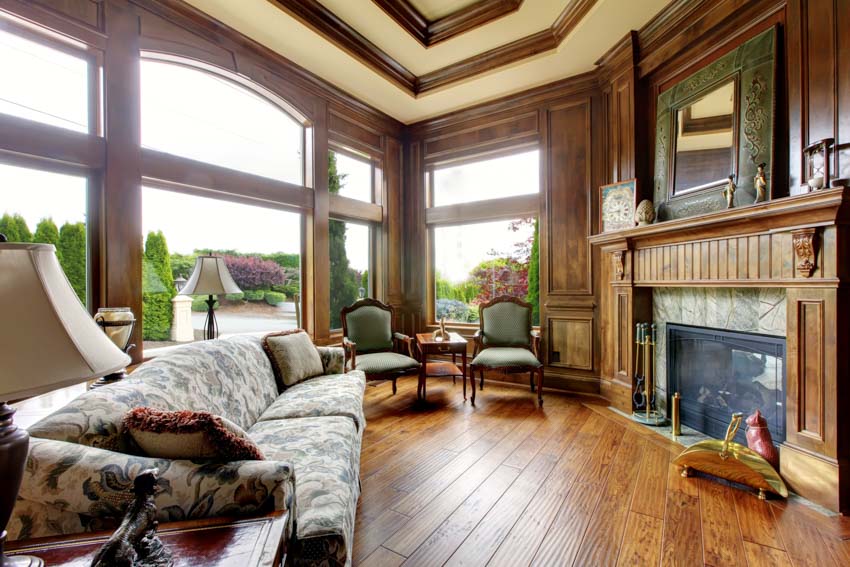 Classic living room with wood molding on ceiling, windows, fireplace, couches, chairs, and lamps