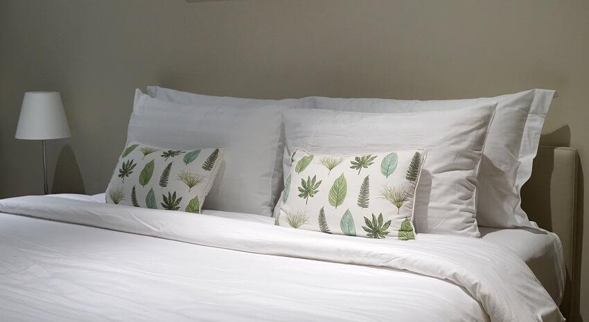 Comfortable throw cushion on the white pillow and bed sheet in the bedroom