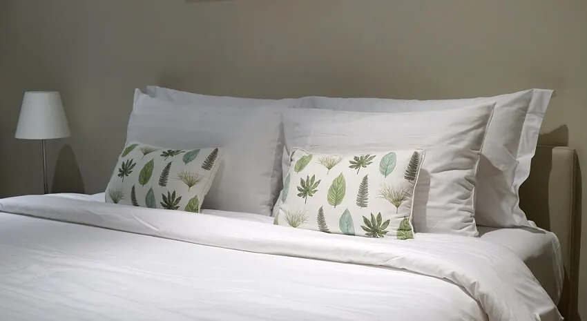 Comfortable throw cushion on the white pillow and bed sheet in the bedroom