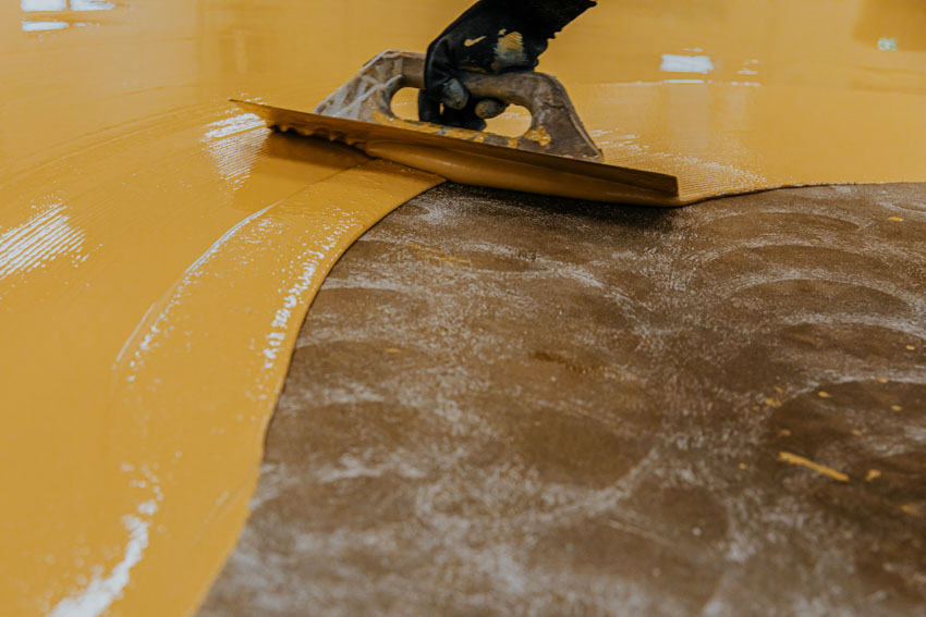 Contractor applying epoxy paint on basement painted floor
