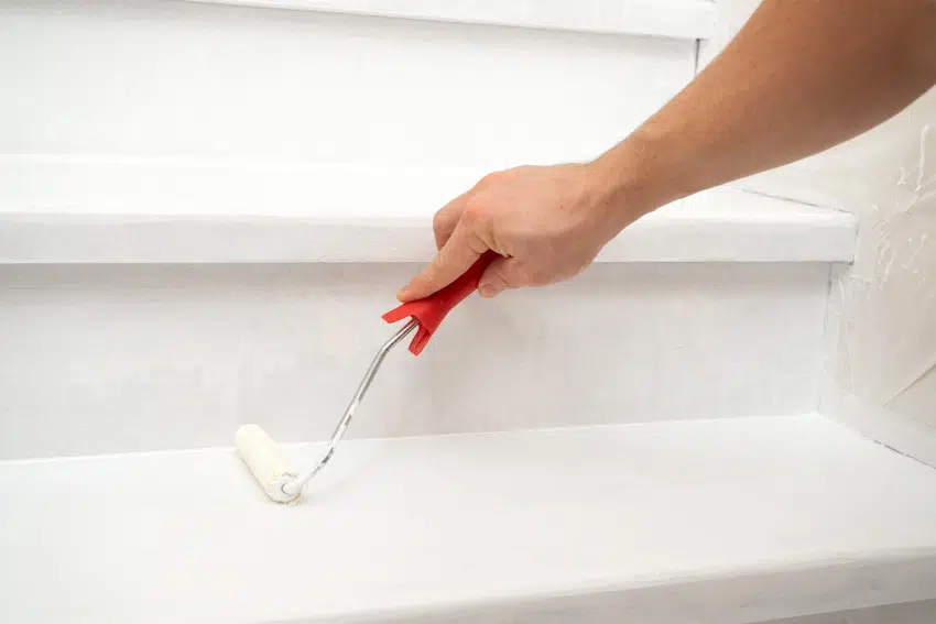 Contractor applying white paint on stairs