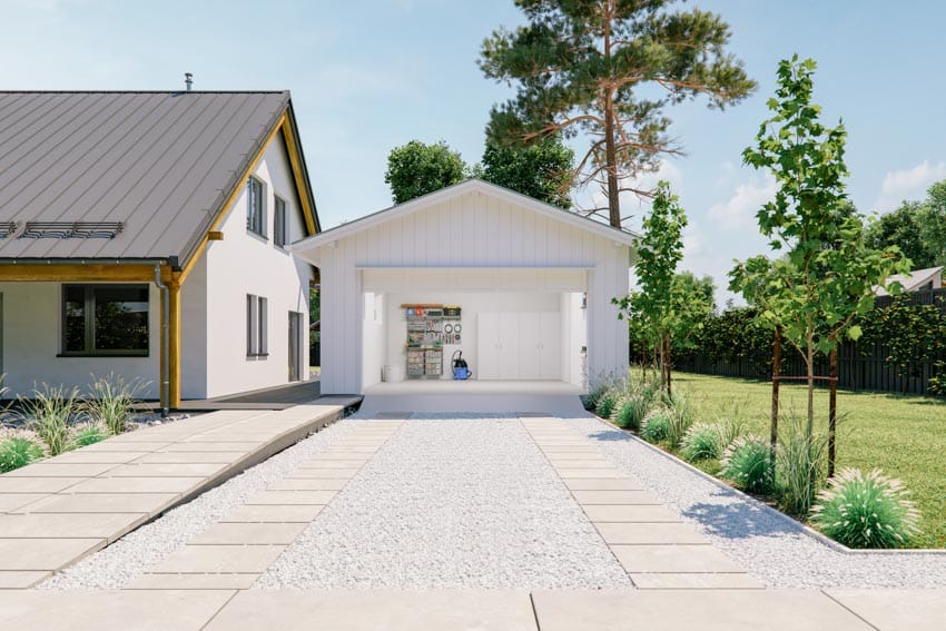 Detached garage with a concrete driveway and pavers next to a house