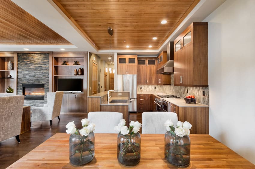 Dining room and kitchen combined with wooden ceiling, cabinets, countertops, table, and chairs