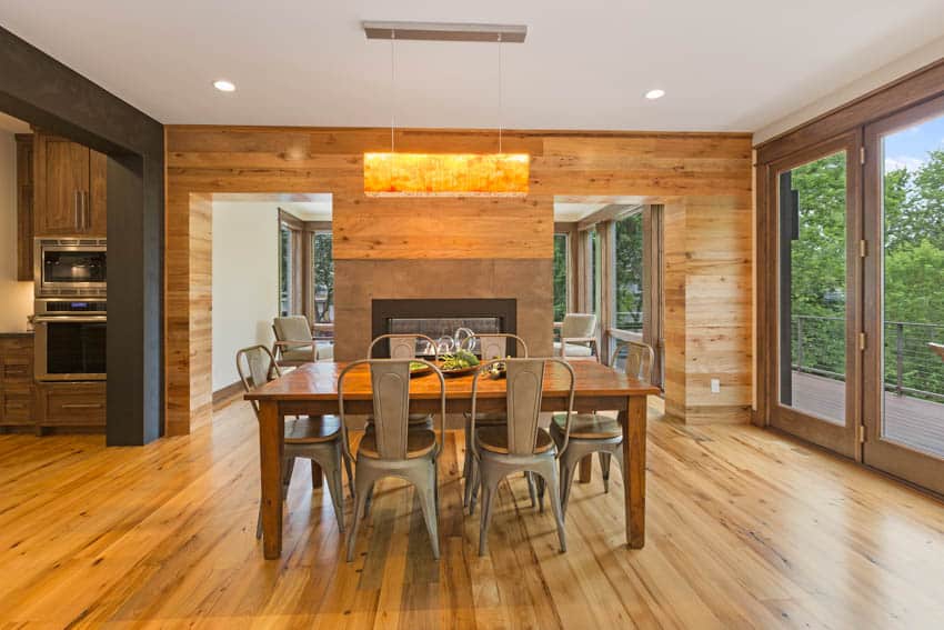 Dining room with wood wall, large glass door, table, chairs, and hanging light