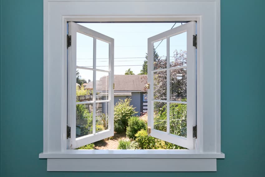 Double white casement windows installed on a blue wall