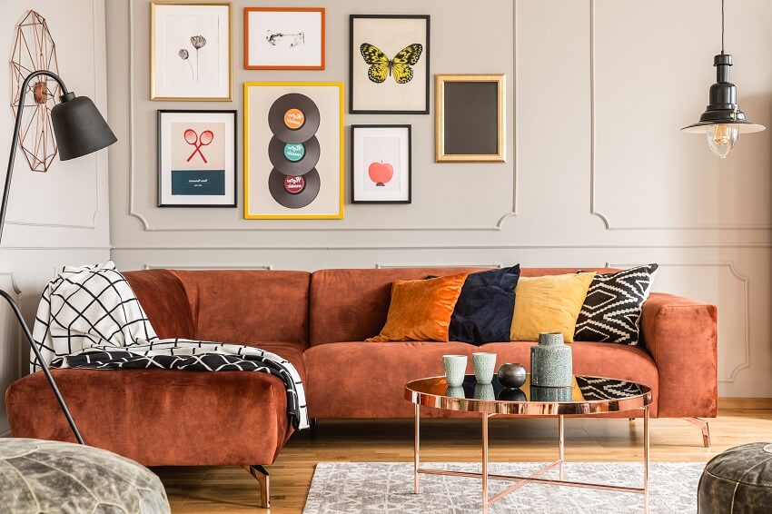 Eclectic living room interior with wood floor lamps wall with molding and frame decors coffee table and a comfortable velvet corner sofa with pillows