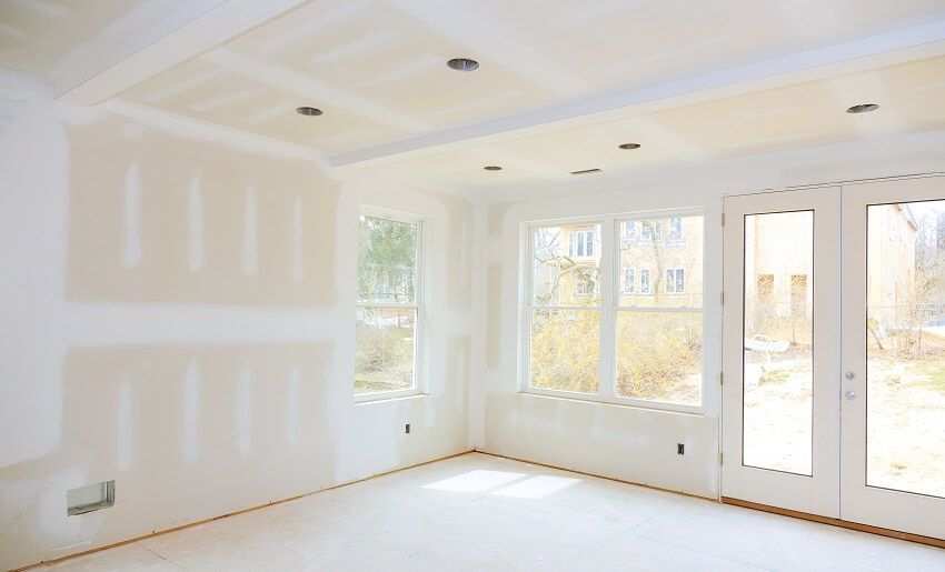 Empty white room under construction with with windows and finished drywall
