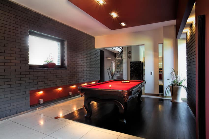Game area with black brick accent wall, red ceiling, and window