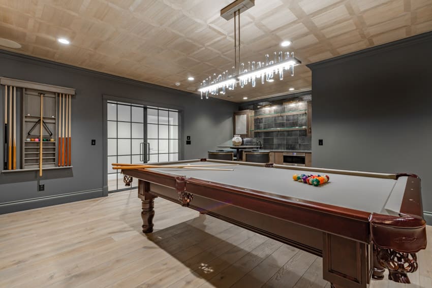 Game room with pool table, hanging light, and cue stick storage