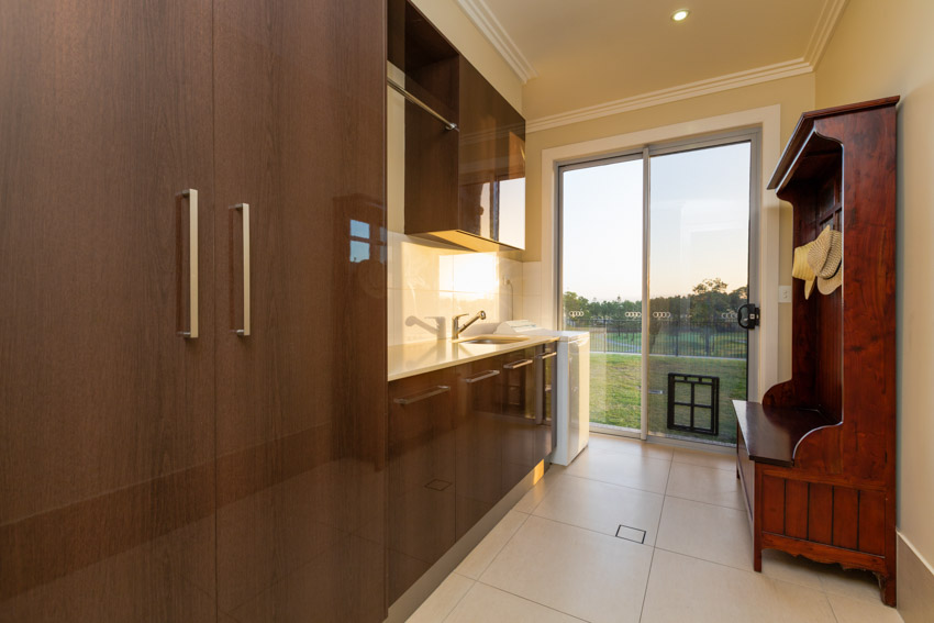 Glass door with dog flap, wood cabinets, kitchen sink, and faucet