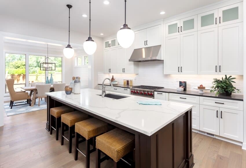 Gorgeous kitchen in new luxury home with island pendant lights and hardwood floors with a view of dining room