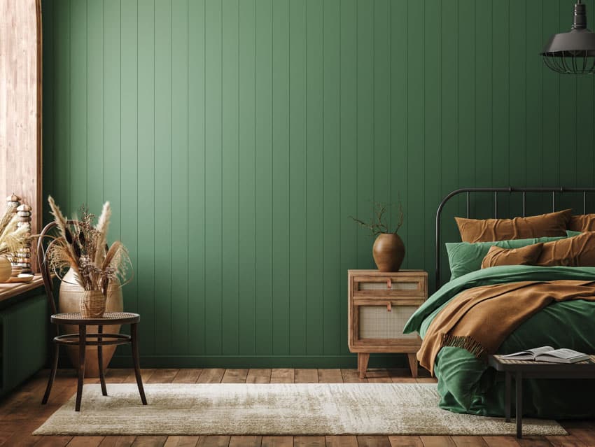 Bedroom with green panel wall, baseboard, window, small drawer, and rug