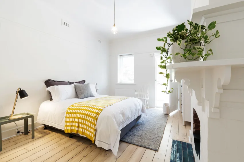 Guest bedroom with wood floor, window, pendant light, nightstand, and floor lamp