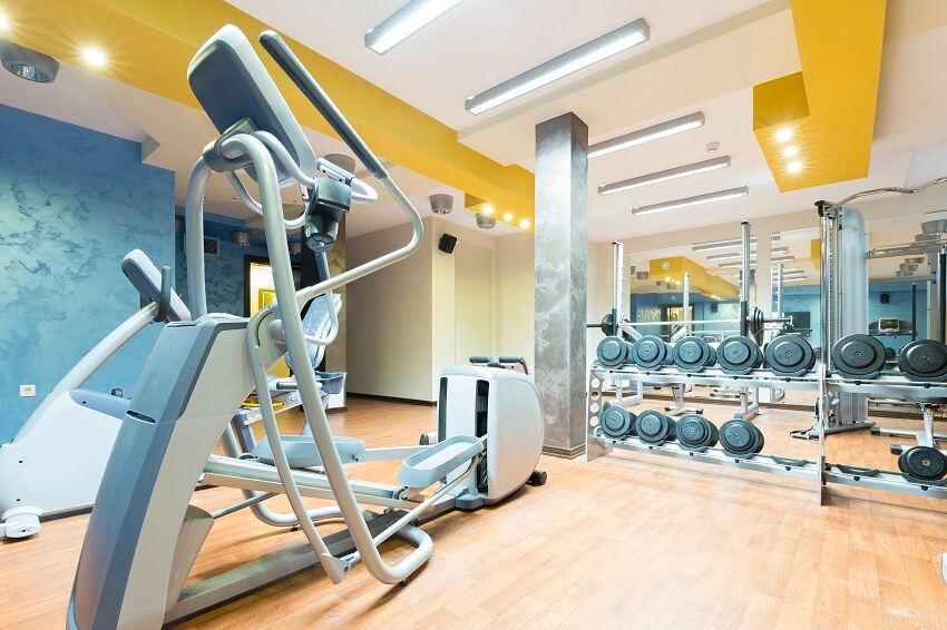 Gym with equipment wood floor grey post yellow beams and recessed and flush mount ceiling lights
