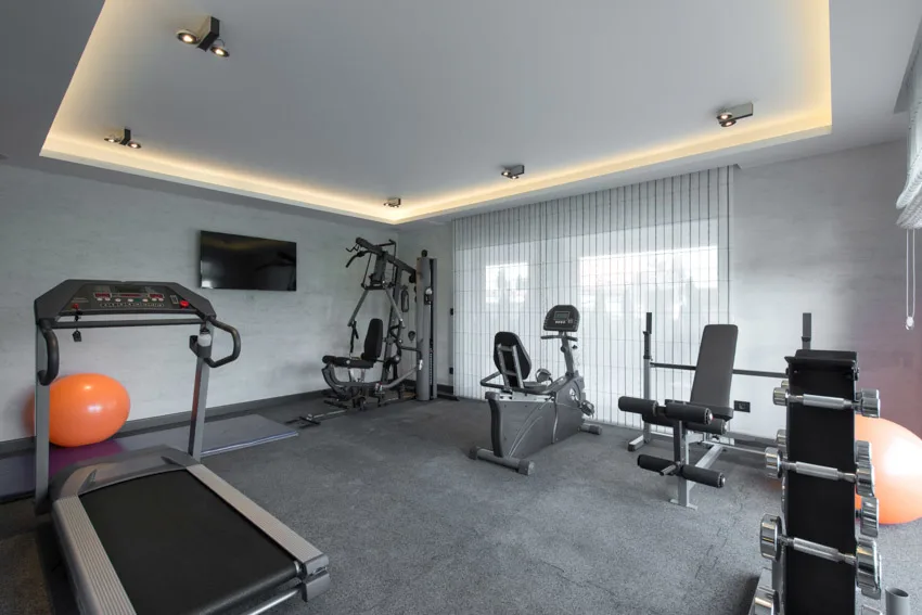 Home office gym with wall mounted television, fitness equipment, and tray ceiling