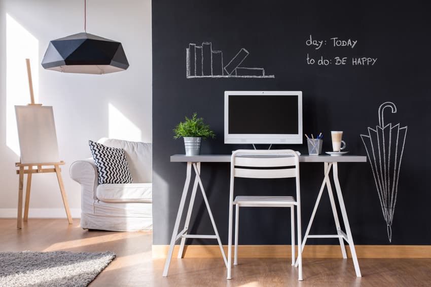 Home office with chalkboard wall, pendant light, wood floor, table, and chair