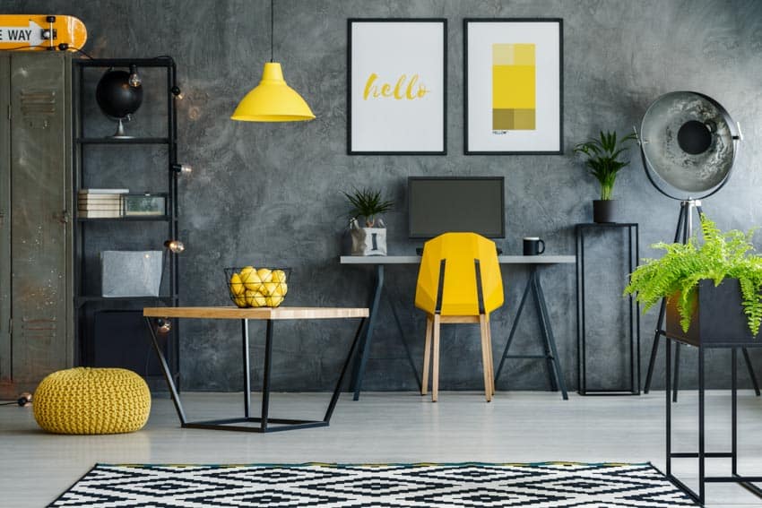 Home office with decor on concrete wall, yellow chair, computer, table, shelves, and floor lamp