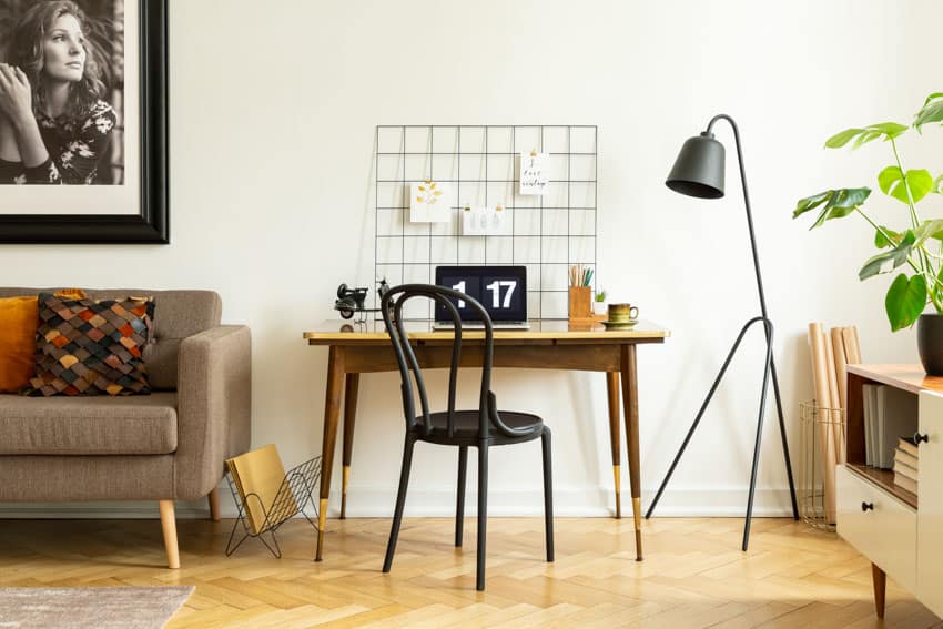 Home office with metal grid wall decor, floor lamp, couch, table, and chair