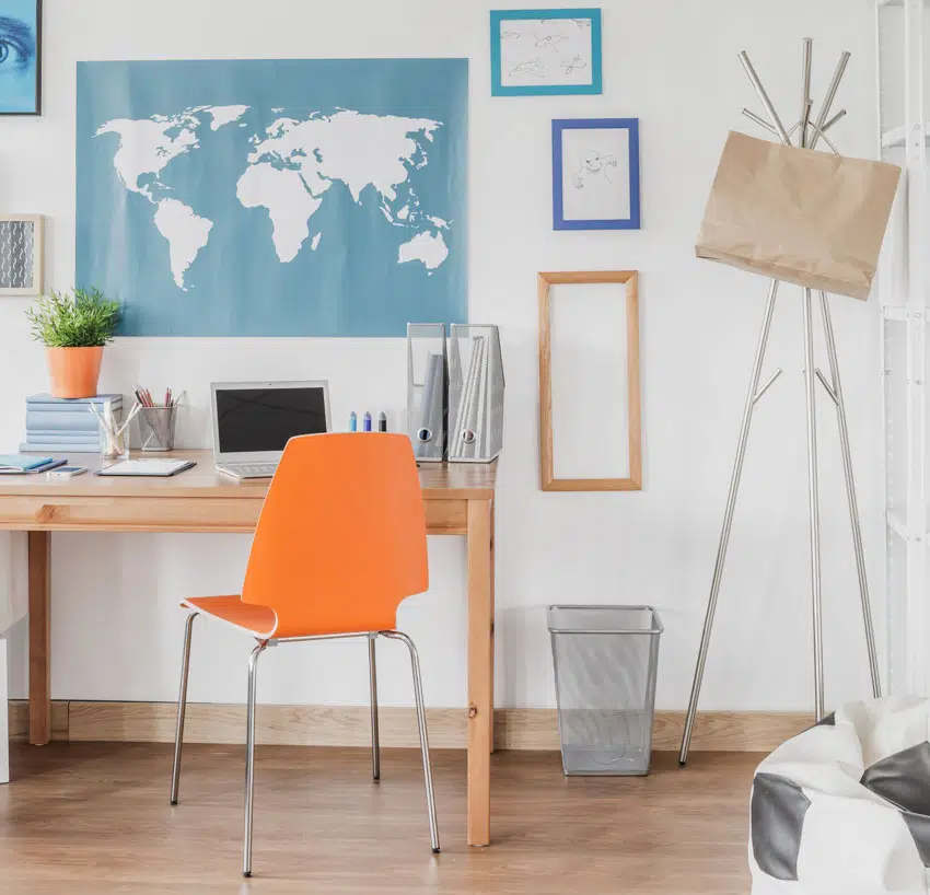 Home office with world map wall decor, frames, wood floor, orange chair, and table