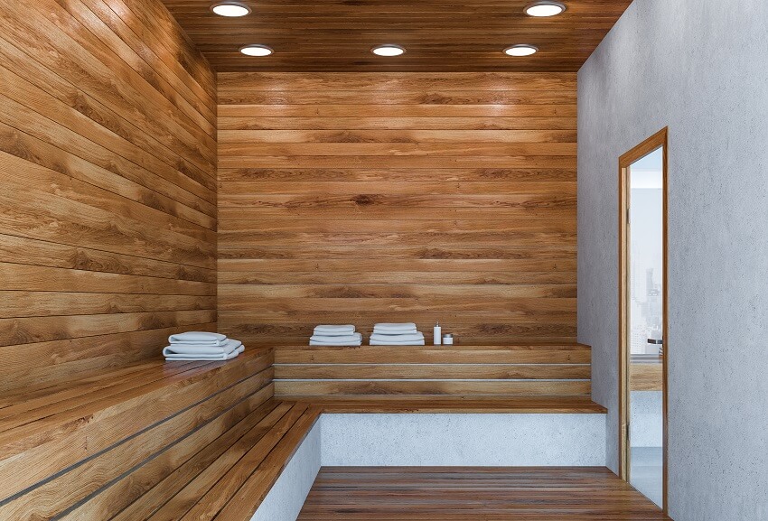 Interior of stylish sauna with wooden and concrete walls wooden floor and benches with stacks of towels on them