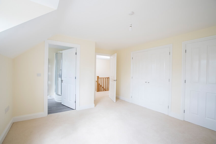 Interior view of an empty bedroom with fitted wardrobes and en suite bathroom