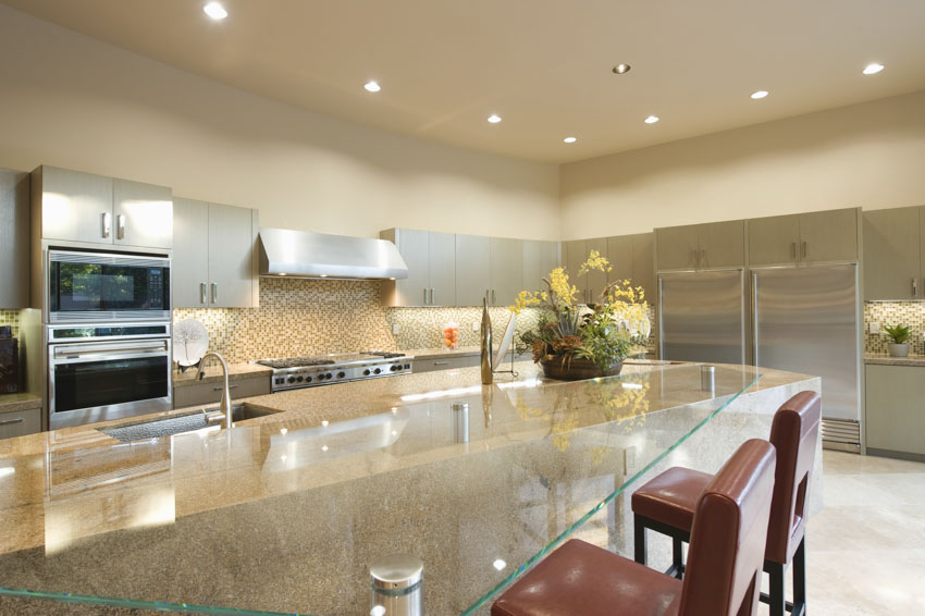 Kitchen and dining room combined with glass table, chairs, recessed lights, hood, oven, and cabinets