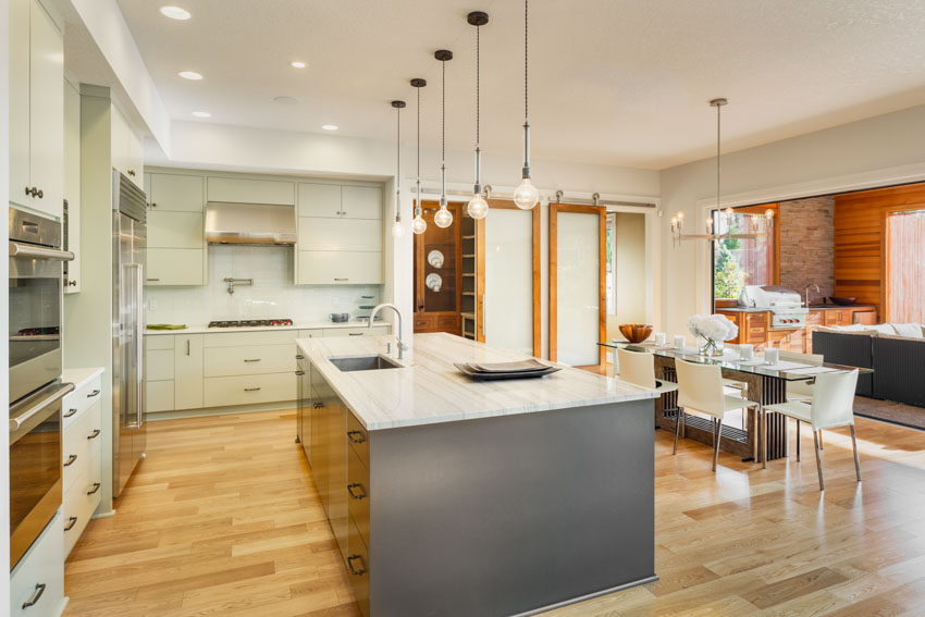 Kitchen space with honed quartzite countertop, pendant lights, wood flooring, and center island